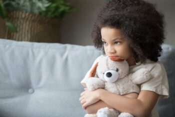 Photo of young girl holding a teddy bear tight
