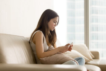 Young woman sitting down using her phone