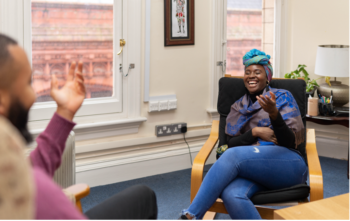 Living Well Uk - laughing and smiling woman sat in chair during a therapy session