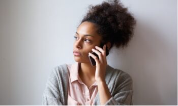 Woman on the phone with a concerned expression making a call to the NHS, Birmingham Mind and Living Well UK mental health helpline